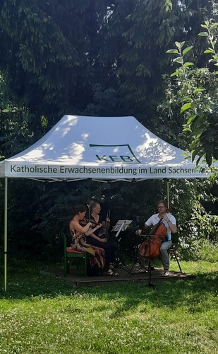 Musiker_innen unter einem Pavillon mit KEB-Schriftzug auf der Wiese