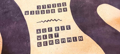 Detail aus Bodenmosaik mit dem Schriftzug "an dieser Stelle auf die Welt gekommen"