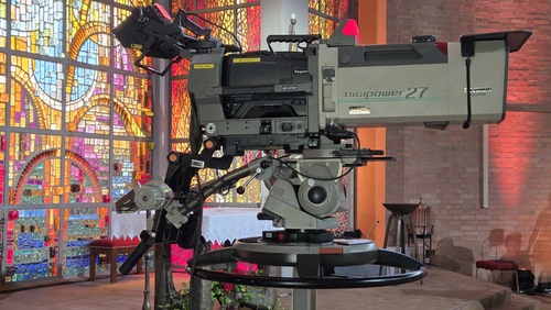 Fernsehkamera in der Kirche vor einem bunten Glasfenster