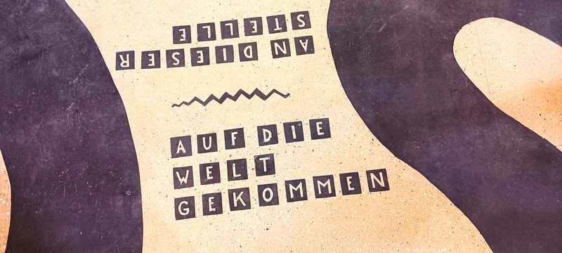 Detail aus Bodenmosaik mit dem Schriftzug "an dieser Stelle auf die Welt gekommen"