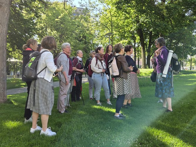 Eine Gruppe von Frauen steht in Sommerkleidung in Basel auf einer Wiese unter Bäumen.