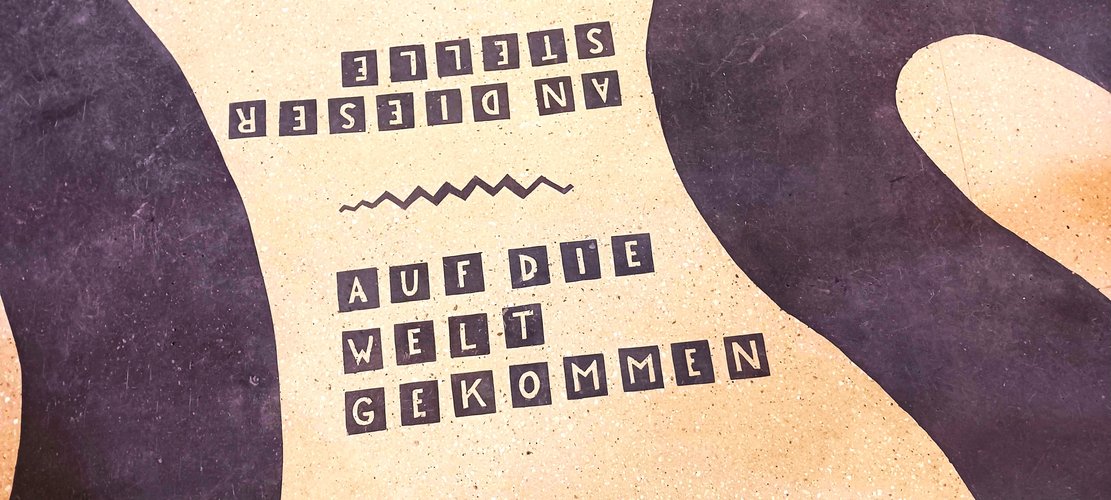 Detail aus Bodenmosaik mit dem Schriftzug "an dieser Stelle auf die Welt gekommen"